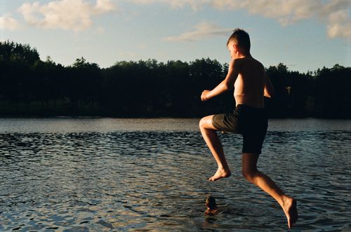 Free A boy joyfully jumps into a scenic lake in Utena County, Lithuania, during summer. Stock Photo