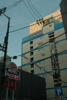 View of a hotel building in Osaka with visible signage and power lines at dusk.