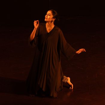 A dancer in a traditional outfit performs gracefully on a dimly lit stage.（イメージ）