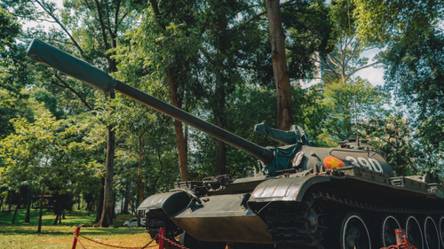 Free A preserved military tank is showcased amidst green trees in a serene park setting. Stock Photo