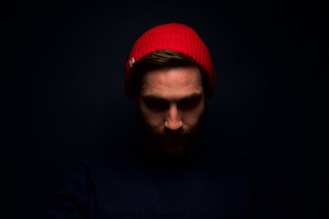 無料 暗室で赤いニット帽をかぶった男 写真素材