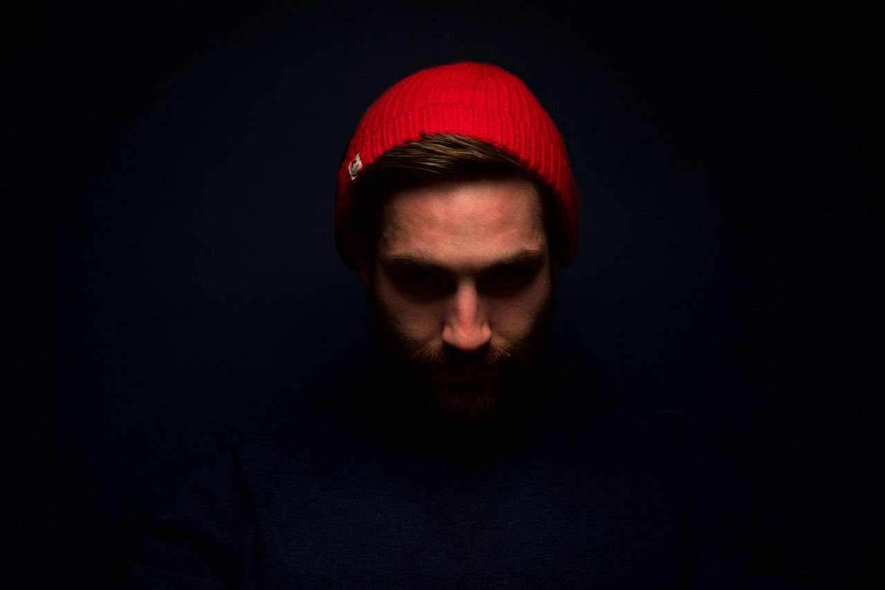 dramatic low key portrait of a man in a red beanie emphasizing shadows