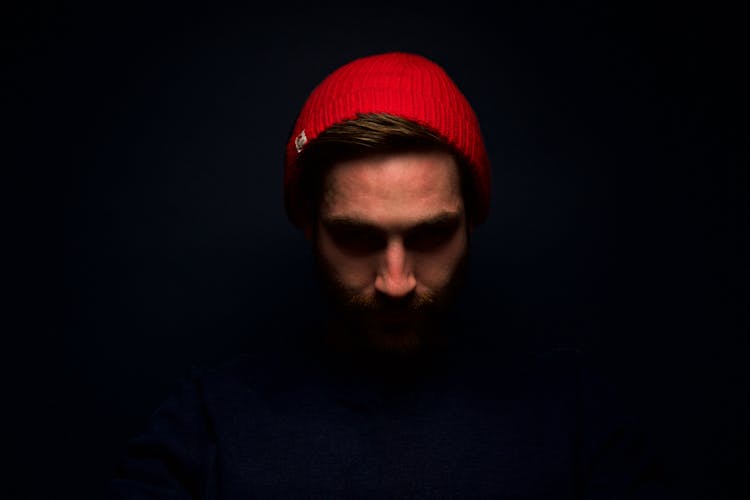 Man Wearing Red Knit Cap In Dark Room