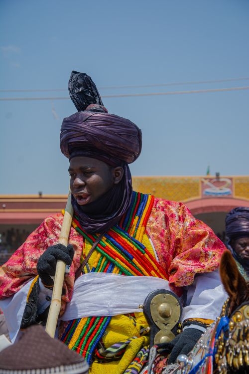 Free Man in vibrant traditional Nigerian attire participates in a cultural festival outdoors. Stock Photo