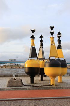 Yellow and black navigation buoys near the sea, offering a vibrant contrast against the sky.
