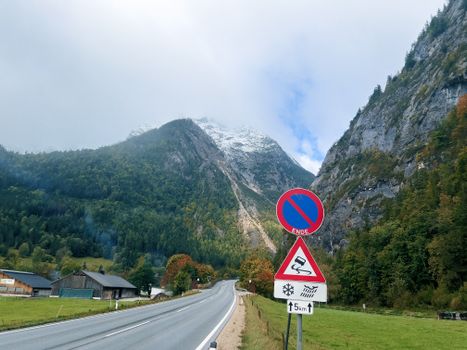 Open road through mountains with no parking sign, surrounded by autumn foliage.