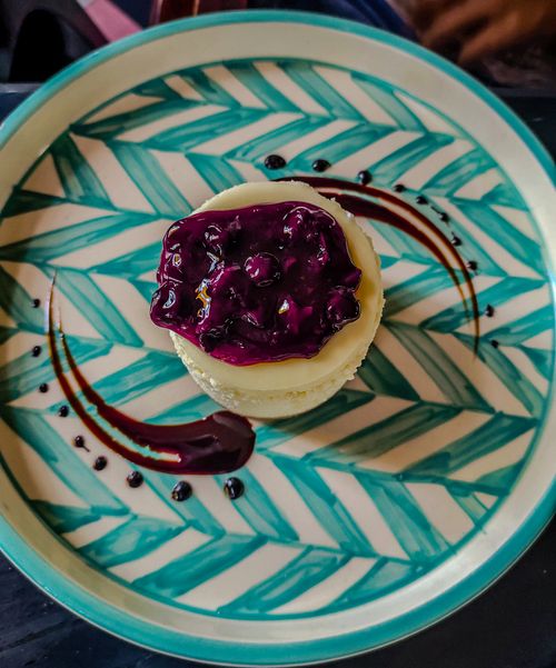 Free Artistic presentation of a blueberry-topped dessert on a modern, patterned plate. Stock Photo