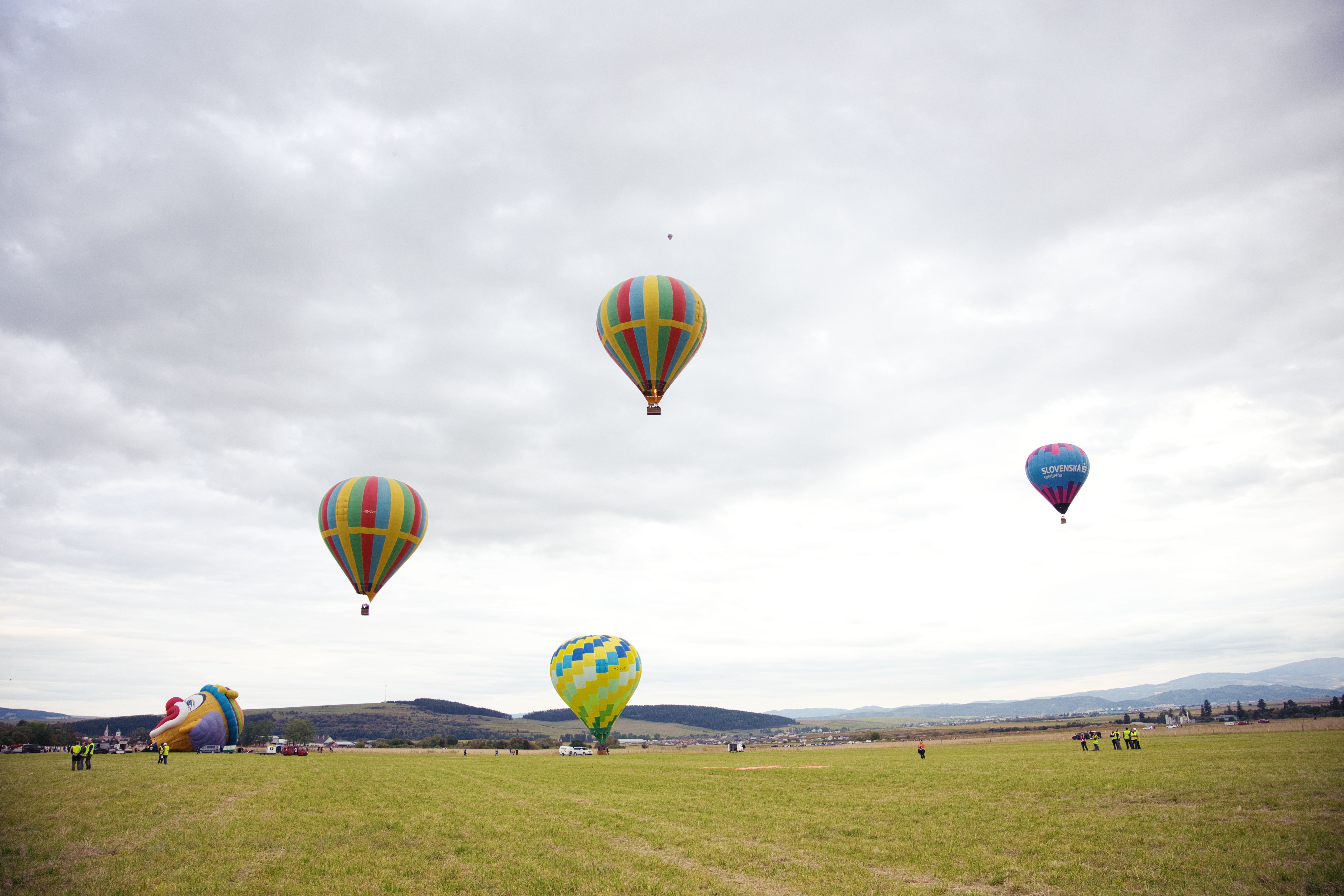 Vibrant hot air balloons float above the fields of Poprad, Slovakia, offering a stunning aerial view.