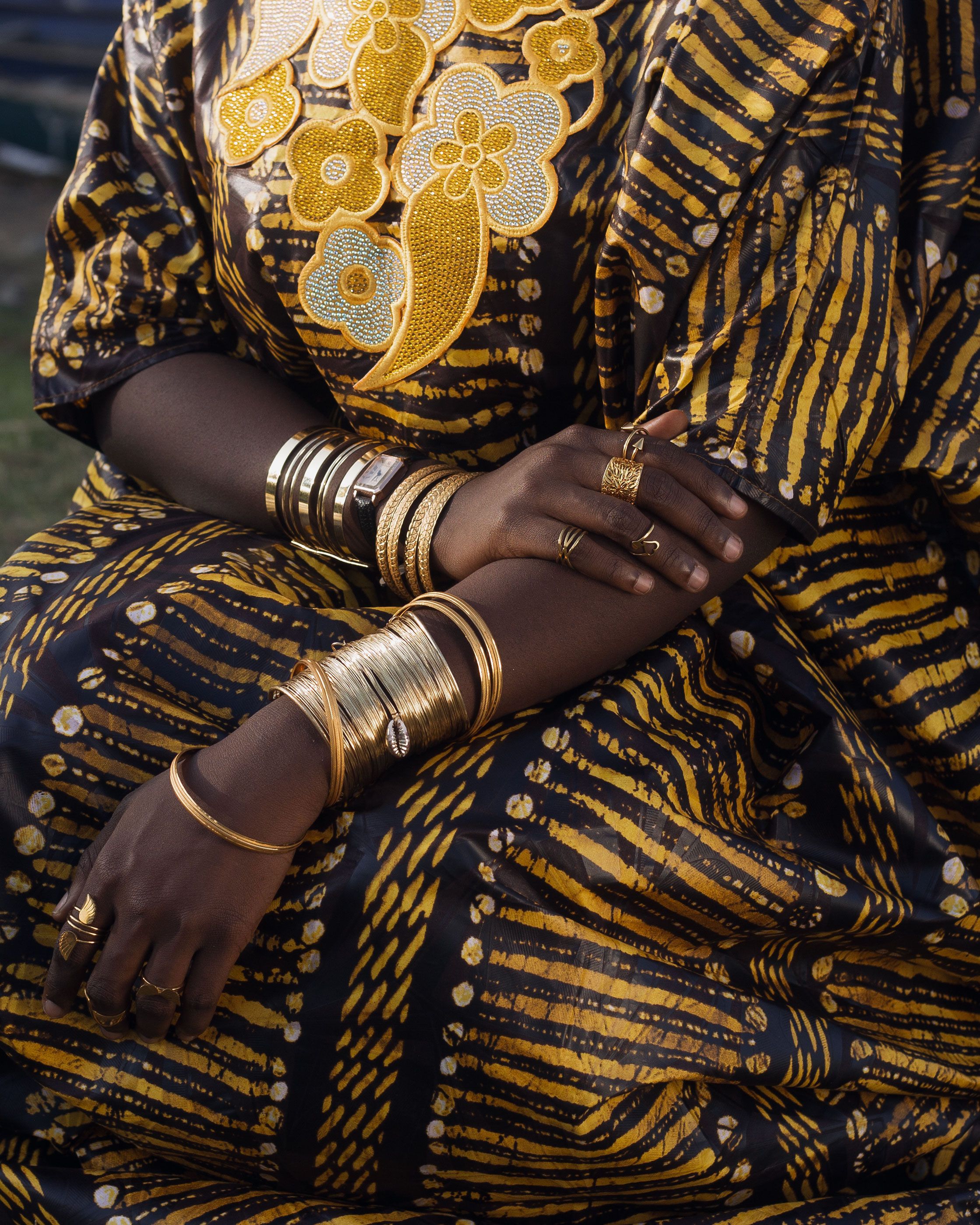 Close-up of a person in African attire adorned with gold jewelry, featuring intricate patterns.