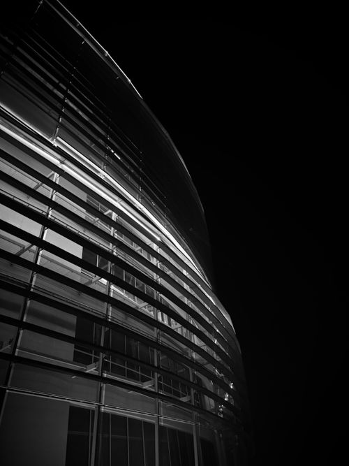 Free Black and white photo of a modern glass building with dramatic lines and lighting at night. Stock Photo