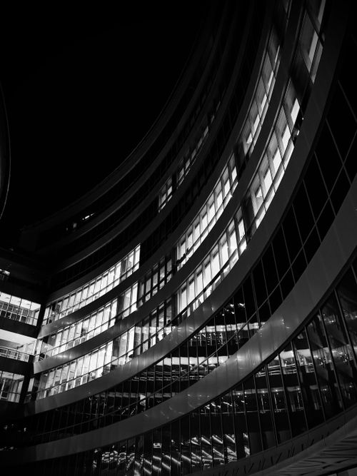 Free A dramatic black and white image of a modern curved building exterior captured at night, highlighting architectural elements. Stock Photo