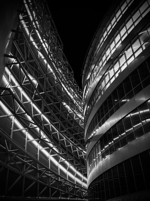 Free A breathtaking black and white shot of modern architecture with geometric lines and illuminated windows. Stock Photo
