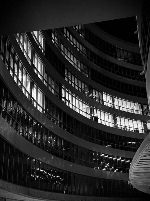 Free Stunning black and white photo of a curved glass building facade illuminated at night. Stock Photo