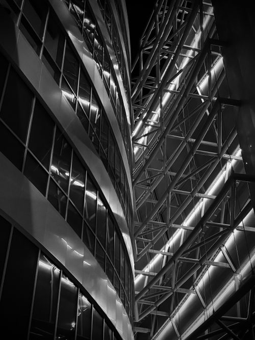 Free A striking view of a futuristic building facade with illuminated beams in a vibrant cityscape. Stock Photo