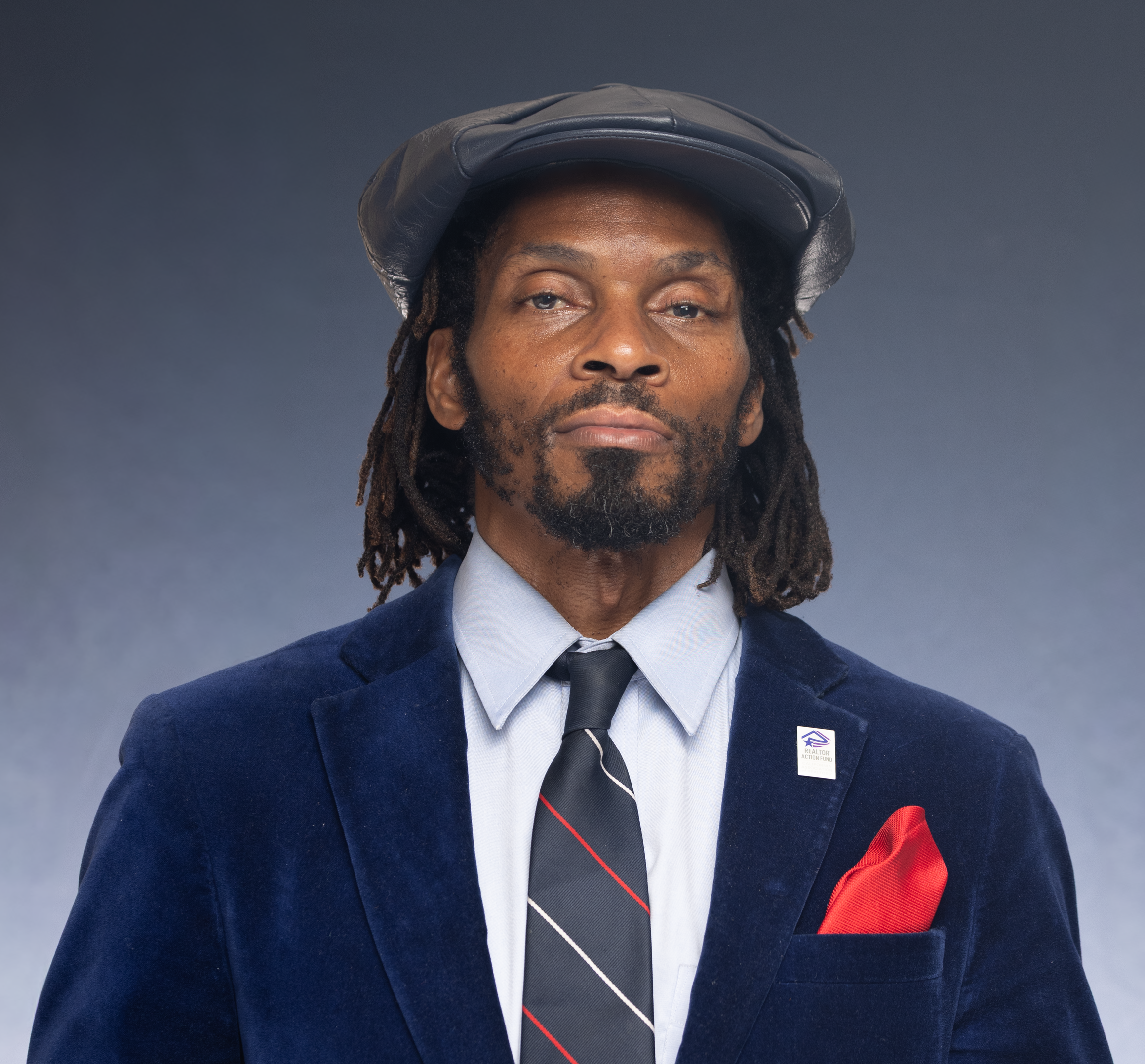 Confident man in formal attire with hat and tie, exuding modern elegance.