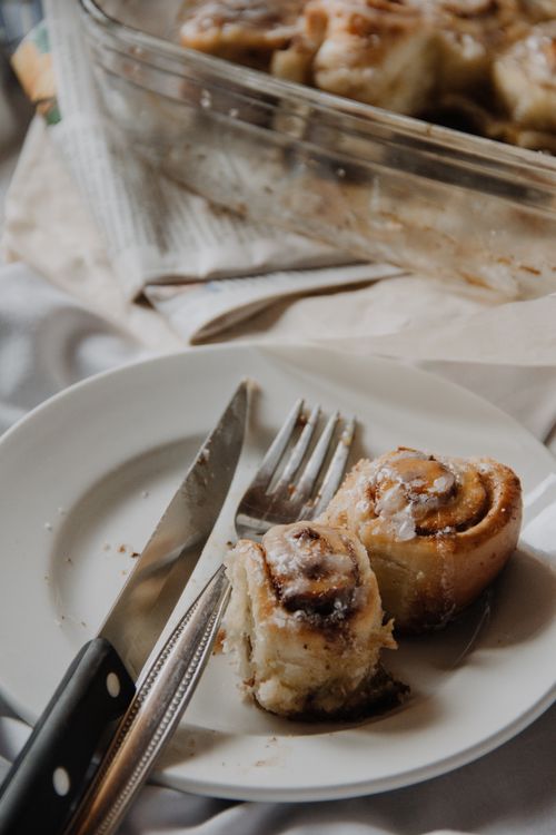 Free Close-up of two cinnamon rolls on a white plate with a fork and knife. Stock Photo