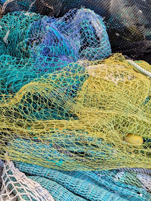 Free Vibrant fishing nets in various colors piled on a dock, showcasing a fishing lifestyle. Stock Photo