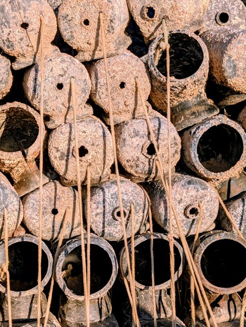Free A close-up view of rustic clay pots stacked together with vertical bamboo sticks, creating an earthy texture. Stock Photo
