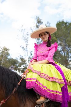 A charra dressed in colorful traditional attire rides a horse during a festival in Dolores Hidalgo, Mexico.