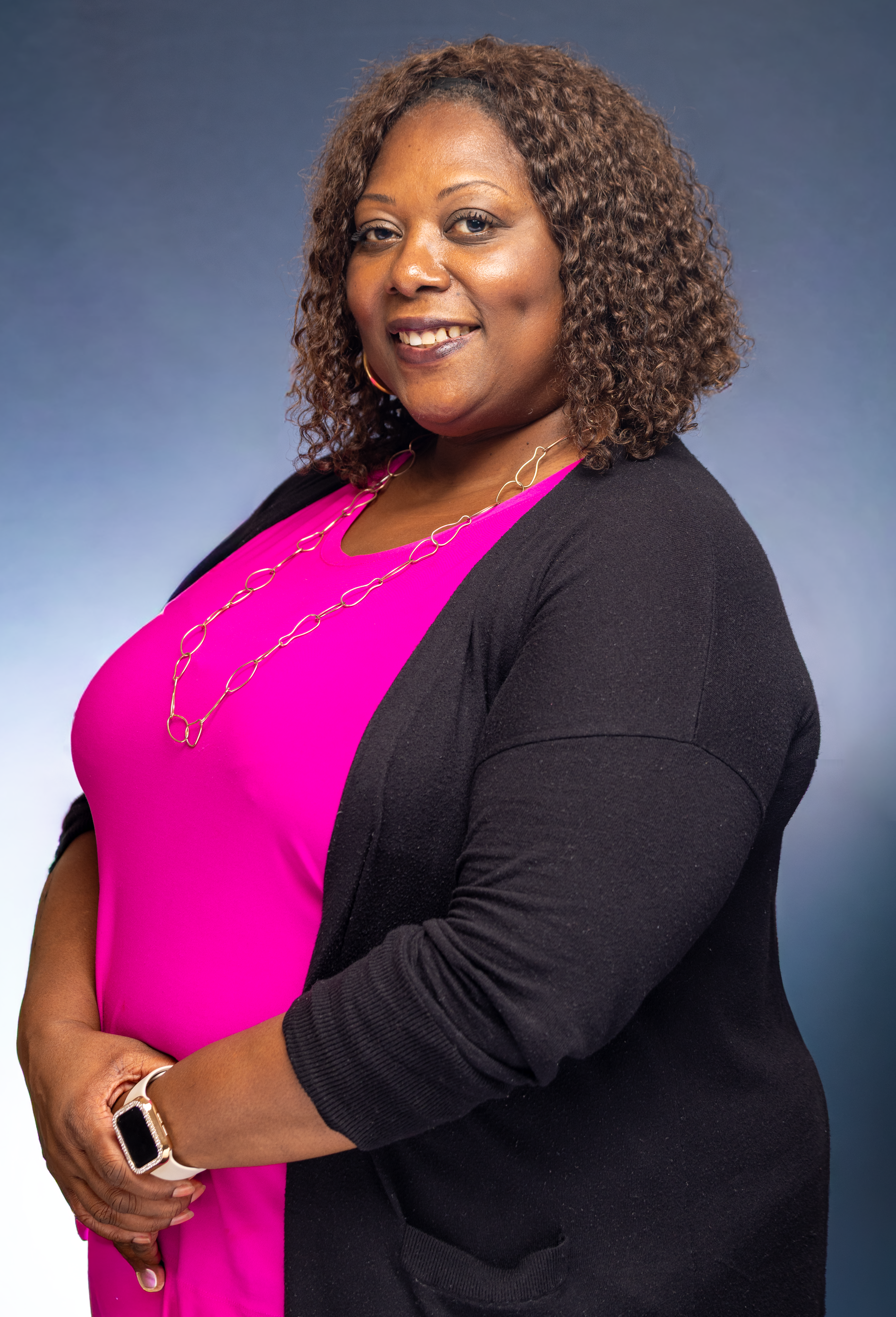 A confident woman smiling in a professional studio portrait with a blue backdrop.
