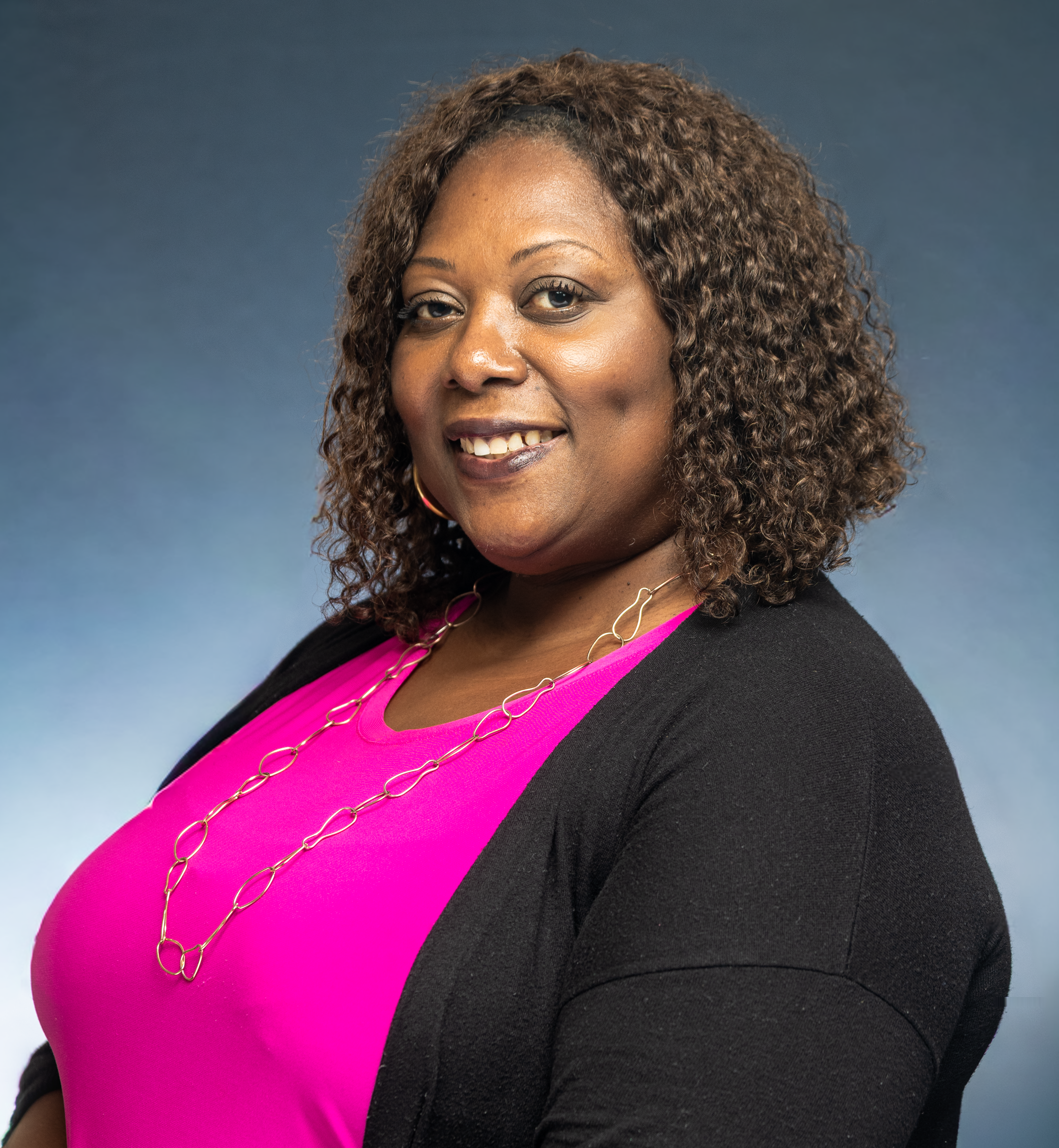 Portrait of a smiling woman in bright attire set against a soft gradient backdrop.