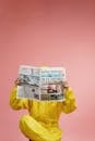 Person in Yellow Coveralls Reading Newspaper