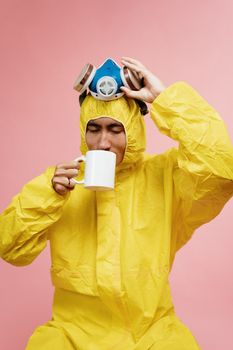 一名身穿黄色防护服的男子戴着呼吸机喝咖啡