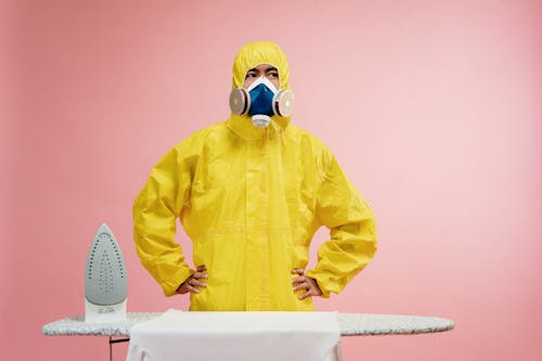 Free Man in Coveralls Standing by Ironing Board Stock Photo