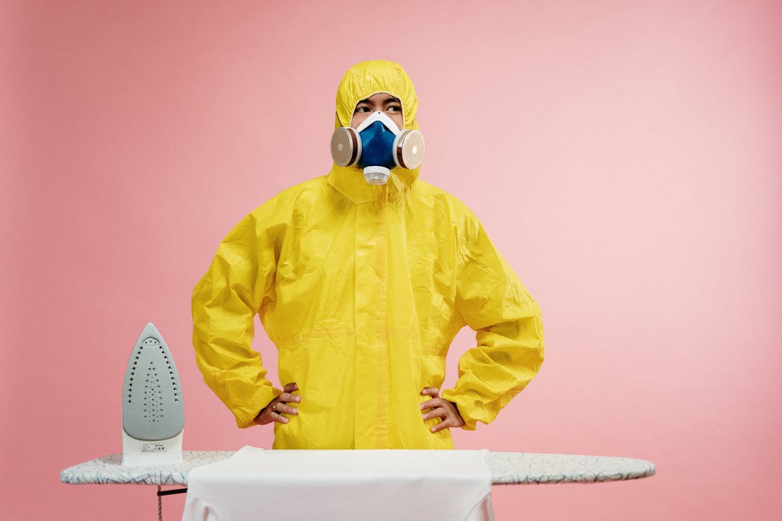 Man in Coveralls Standing by Ironing Board