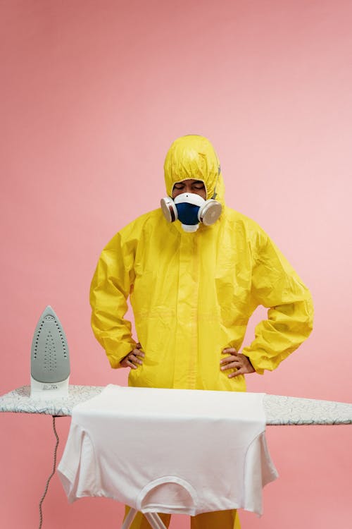 Free Man in Coveralls Standing by Ironing Board Stock Photo