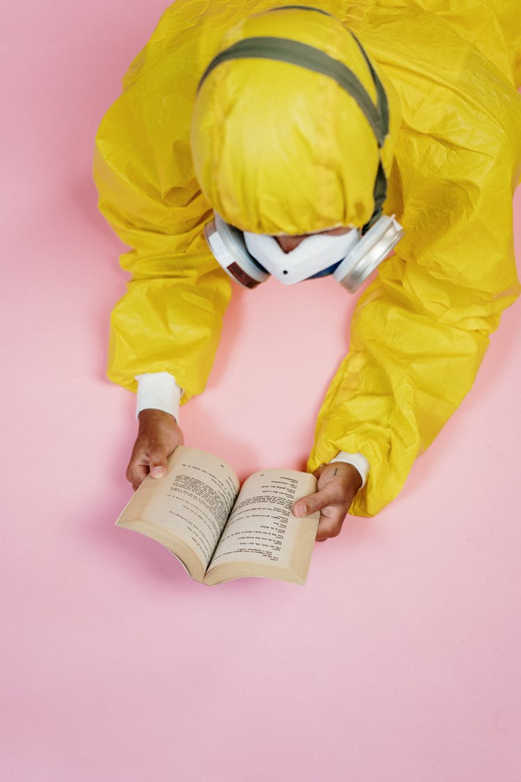 Person In Yellow Protective Suit Reading A Book