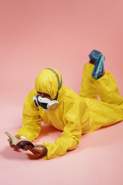 Free Person in Yellow Coveralls Reading a Book Stock Photo