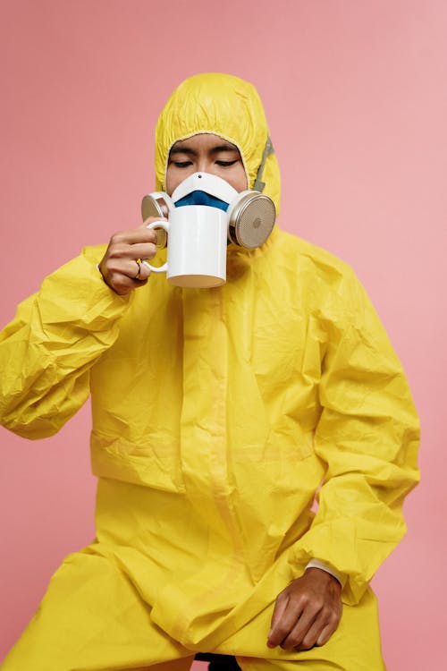 Free Person In Yellow Protective Suit Drinking Stock Photo
