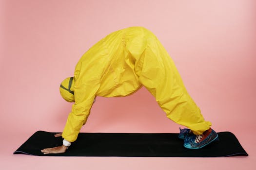Person practicing yoga in PPE suit on a pink backdrop.