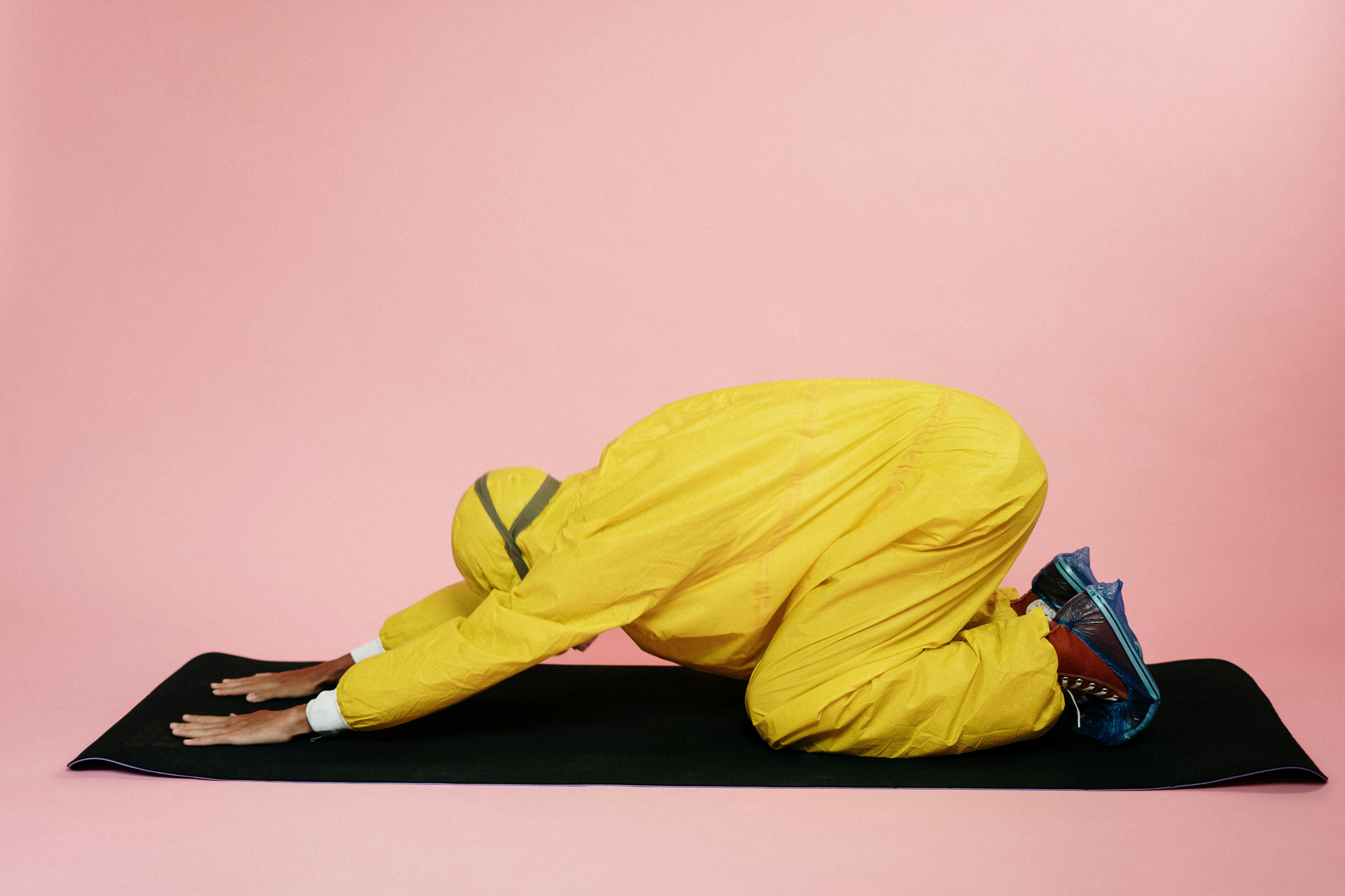 person in yellow protective suit doing a yoga pose