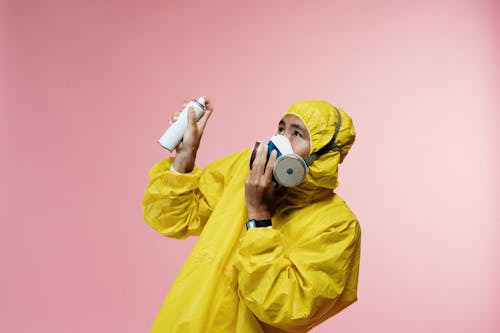 Free Person In Coveralls Holding Spray Bottle Stock Photo