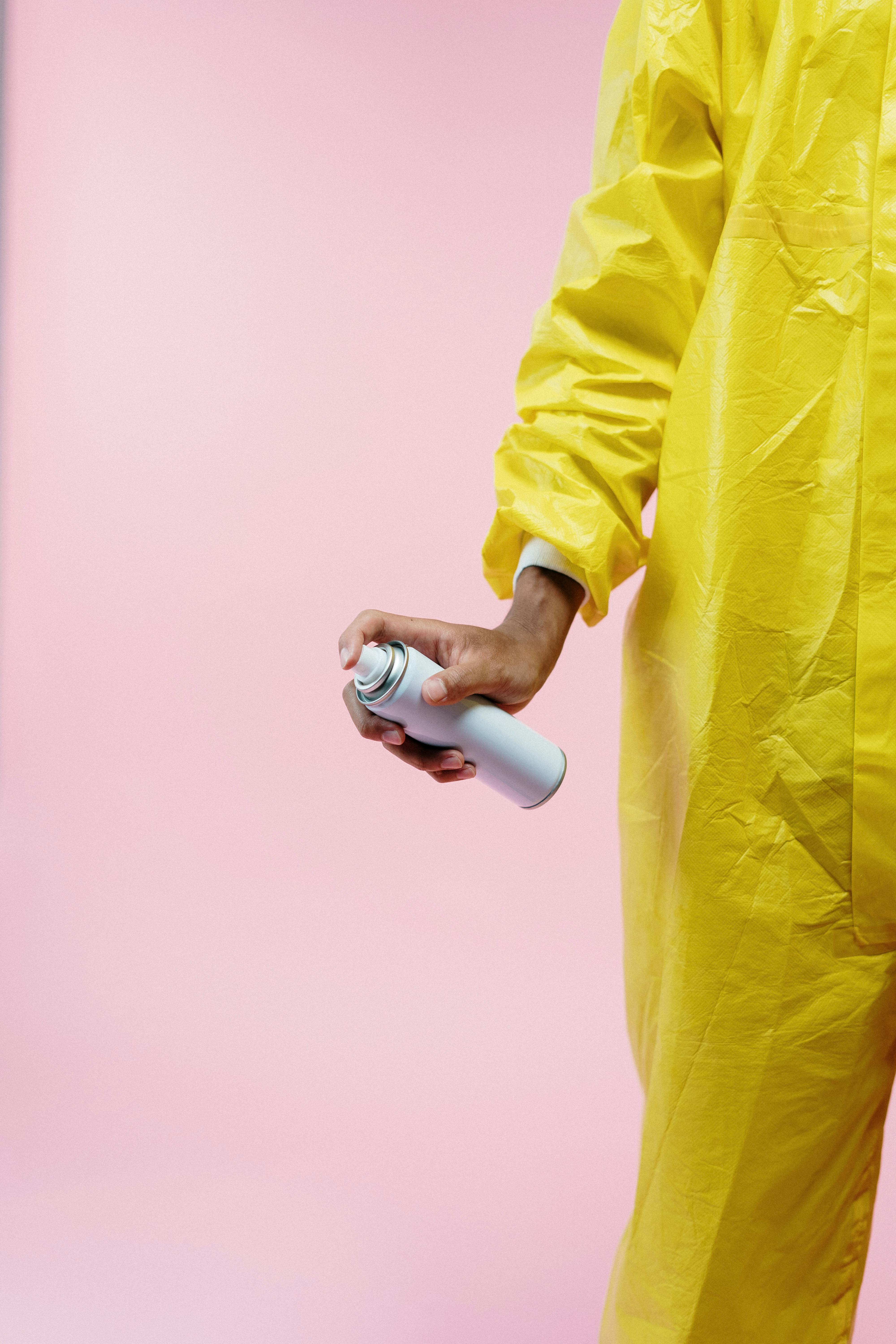 person in yellow protective suit holding aerosol can