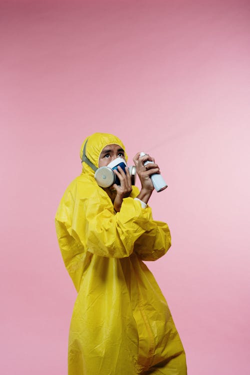 Free Person in Yellow Coveralls Holding Spray Bottle Stock Photo