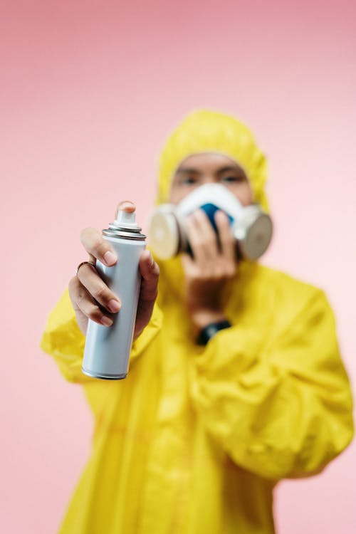 Free Person In Yellow Protection Suit Holding A Spray Can Stock Photo