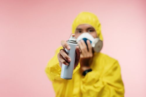 Free Individual in yellow hazmat suit sprays disinfectant, focusing on hygiene and safety. Stock Photo
