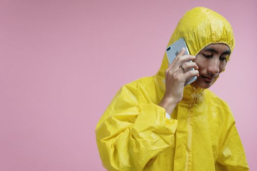 一名身穿防护服的男子在粉色背景前打电话