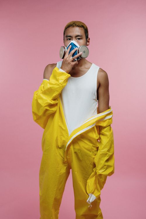 Free Portrait of a man in a yellow protective suit and respirator against pink background. Stock Photo