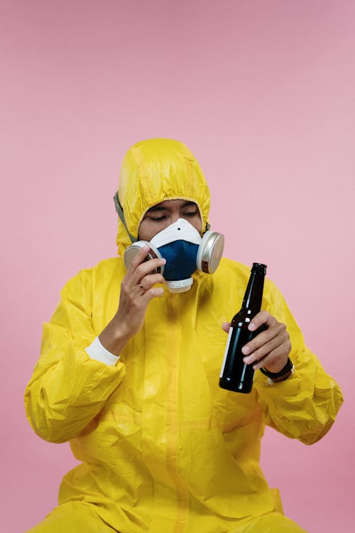 Free Person in Yellow Coveralls Holding Beer Bottle Stock Photo
