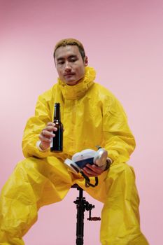一名身穿黄色防护服的男子手持啤酒，这反映了疫情时代