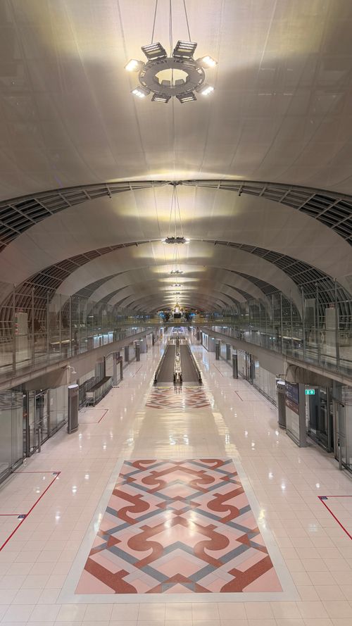 Free A modern train station interior with high vaulted ceilings and patterned floor tiles at nighttime. Stock Photo