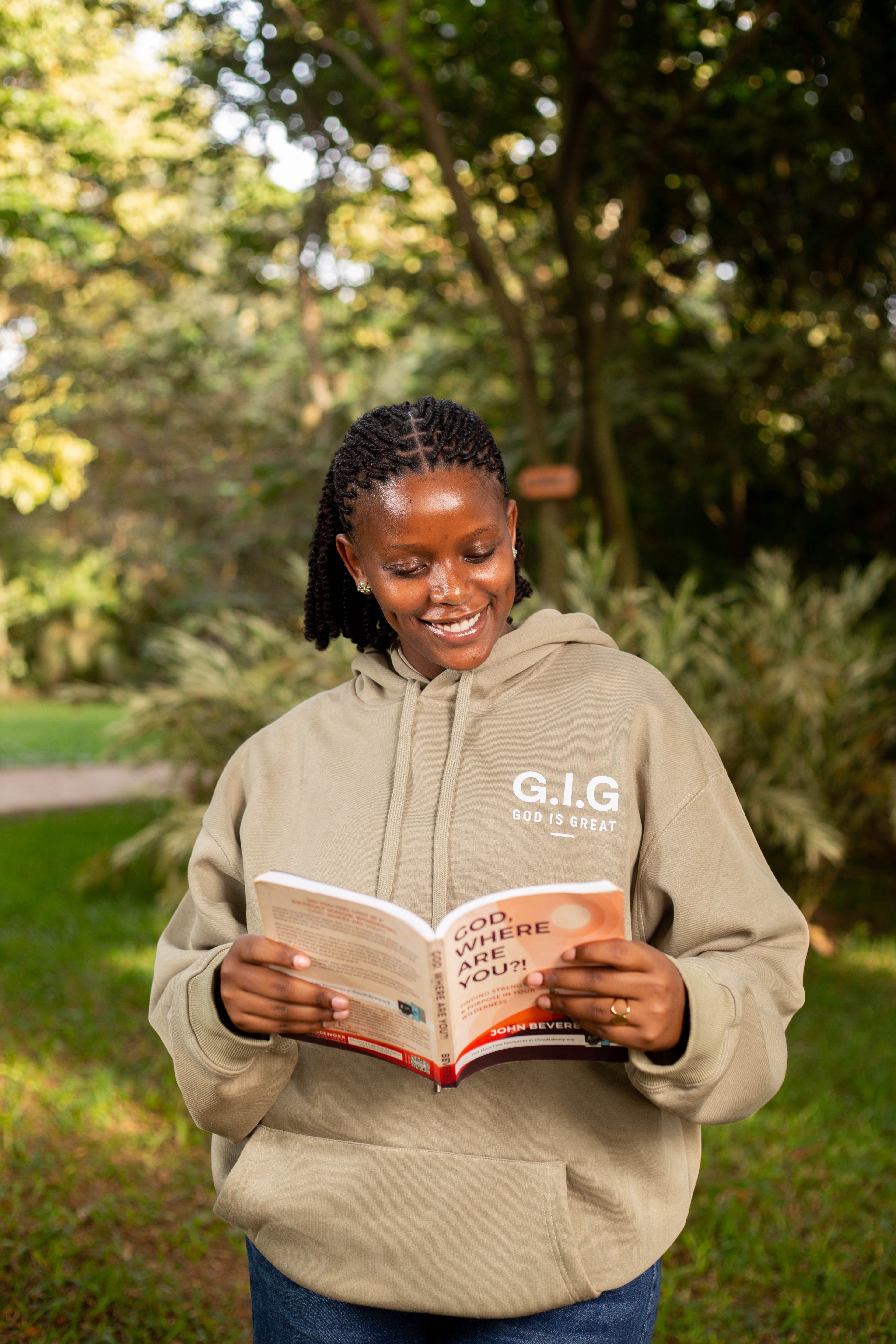 Smiling young woman enjoying a book outdoors on a sunny day.