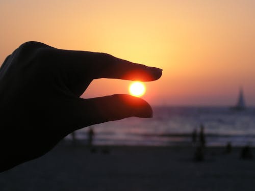 бесплатная Фотография человека, держащего солнце, в перспективе силы Стоковое фото