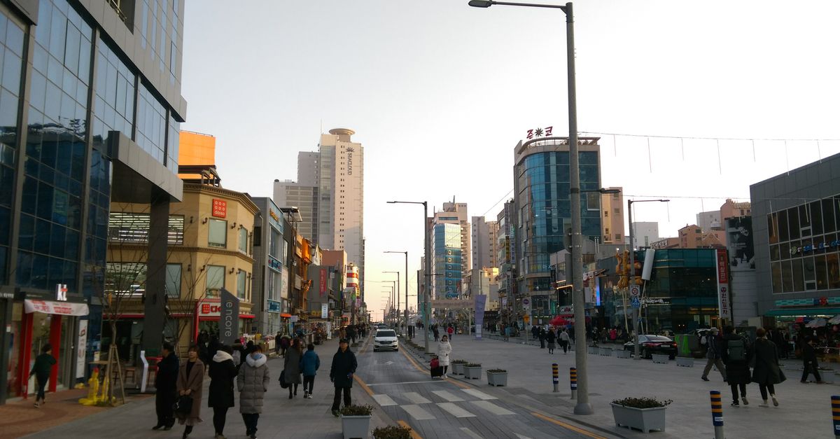 Downtown Busan street view with people and modern buildings at day.