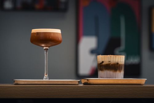 Free Artistic presentation of two specialty coffee drinks in a cozy cafe setting, perfect for gourmet coffee lovers. Stock Photo
