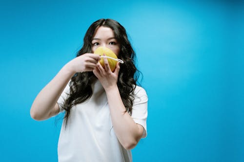 Woman in White Shirt Holding Yellow Fruit